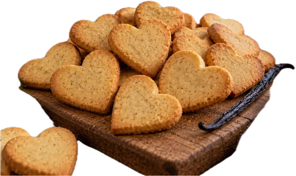Herzförmige Butterplätzchen auf einem Holzbrett mit Vanilleschote